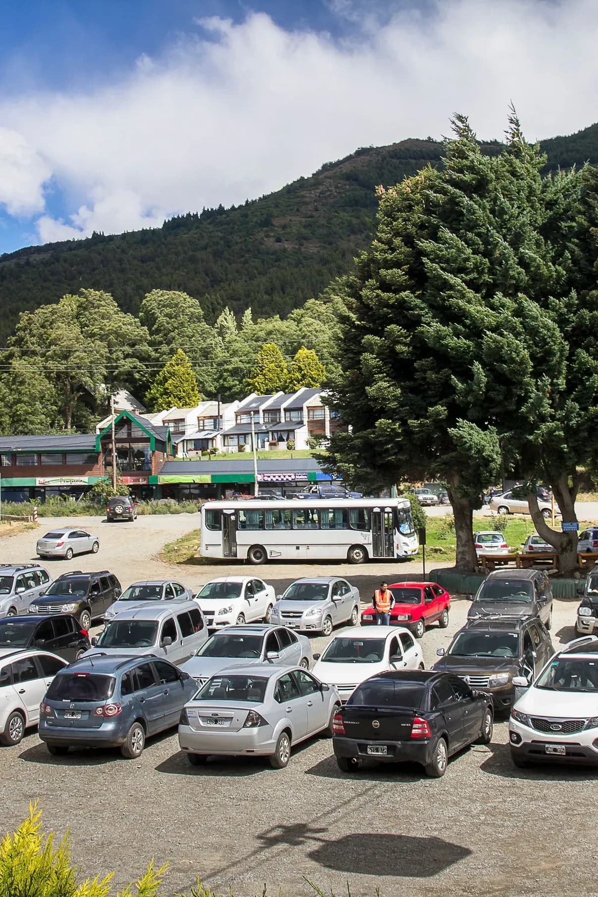 Estacionamiento de la base del Teleférico Cerro Otto con un teleférico ascendiendo y autos debajo